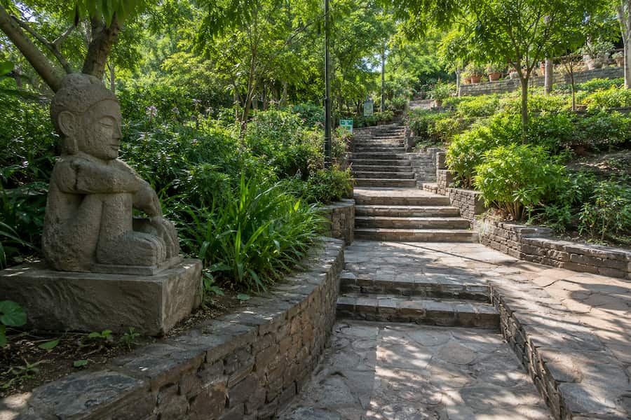 Landscaped pathway and stone sculpture inside the Garden of Five Senses, South Delhi.